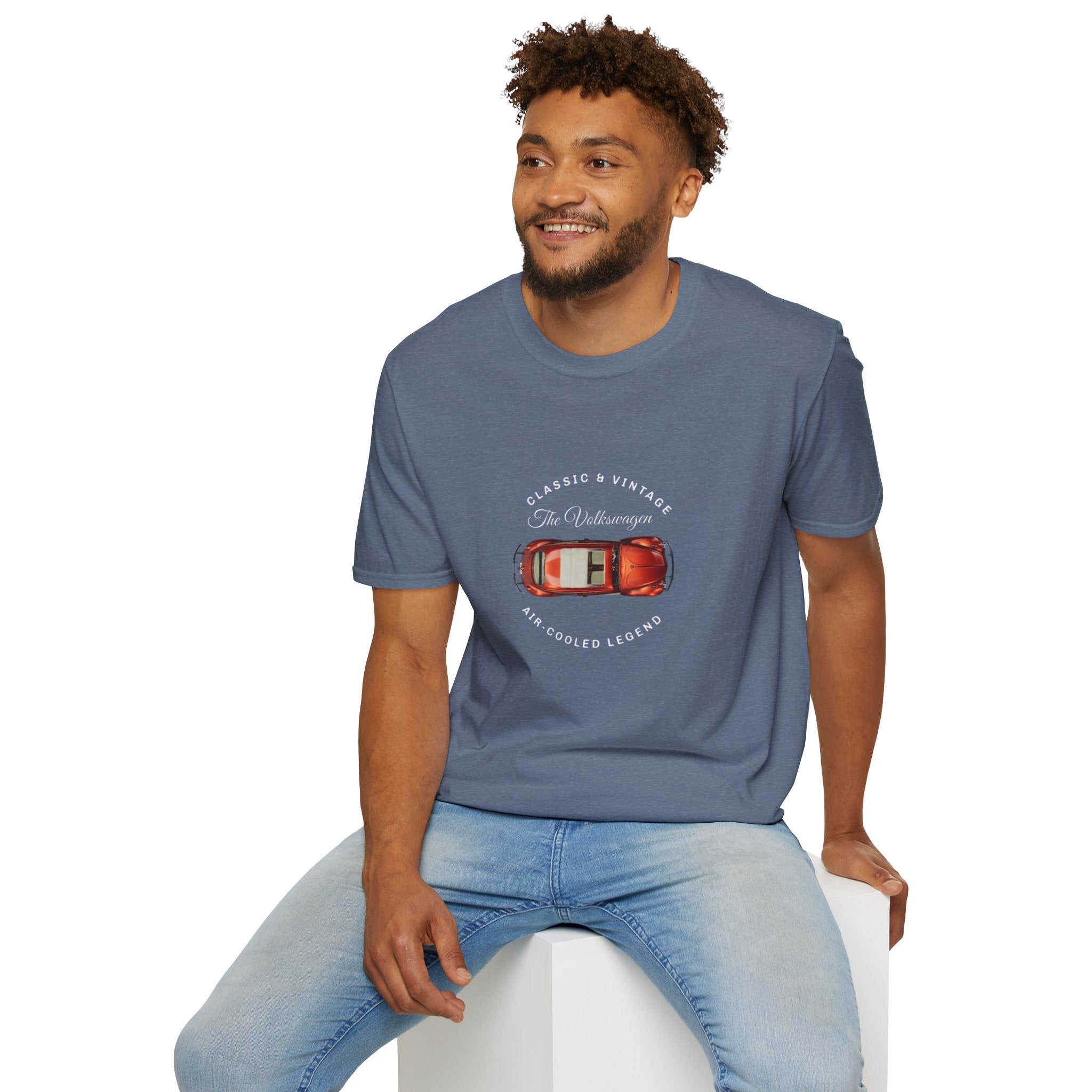Man wearing a blue t-shirt with a VW car graphic and text, sitting on a white stool against a white background.