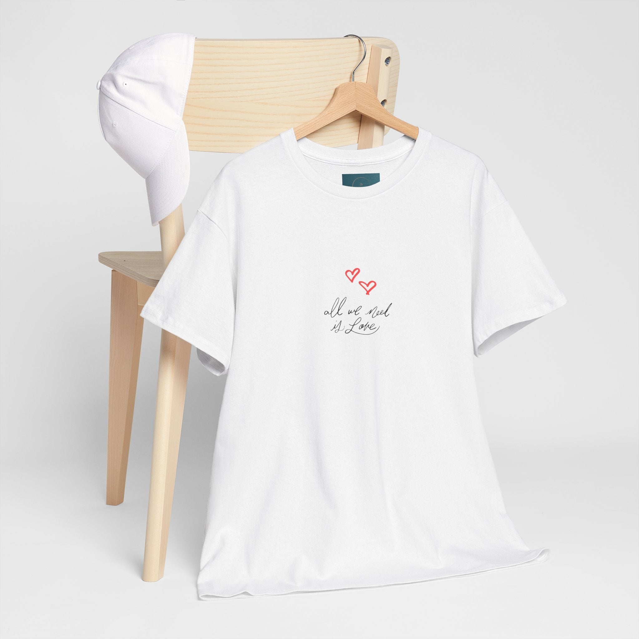 White t-shirt with text and heart design on a wooden chair against a white background