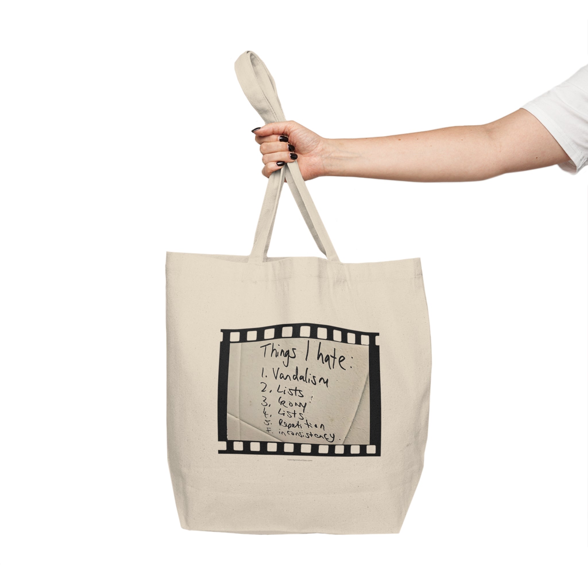 Beige tote bag with black text and design held by a hand on a white background