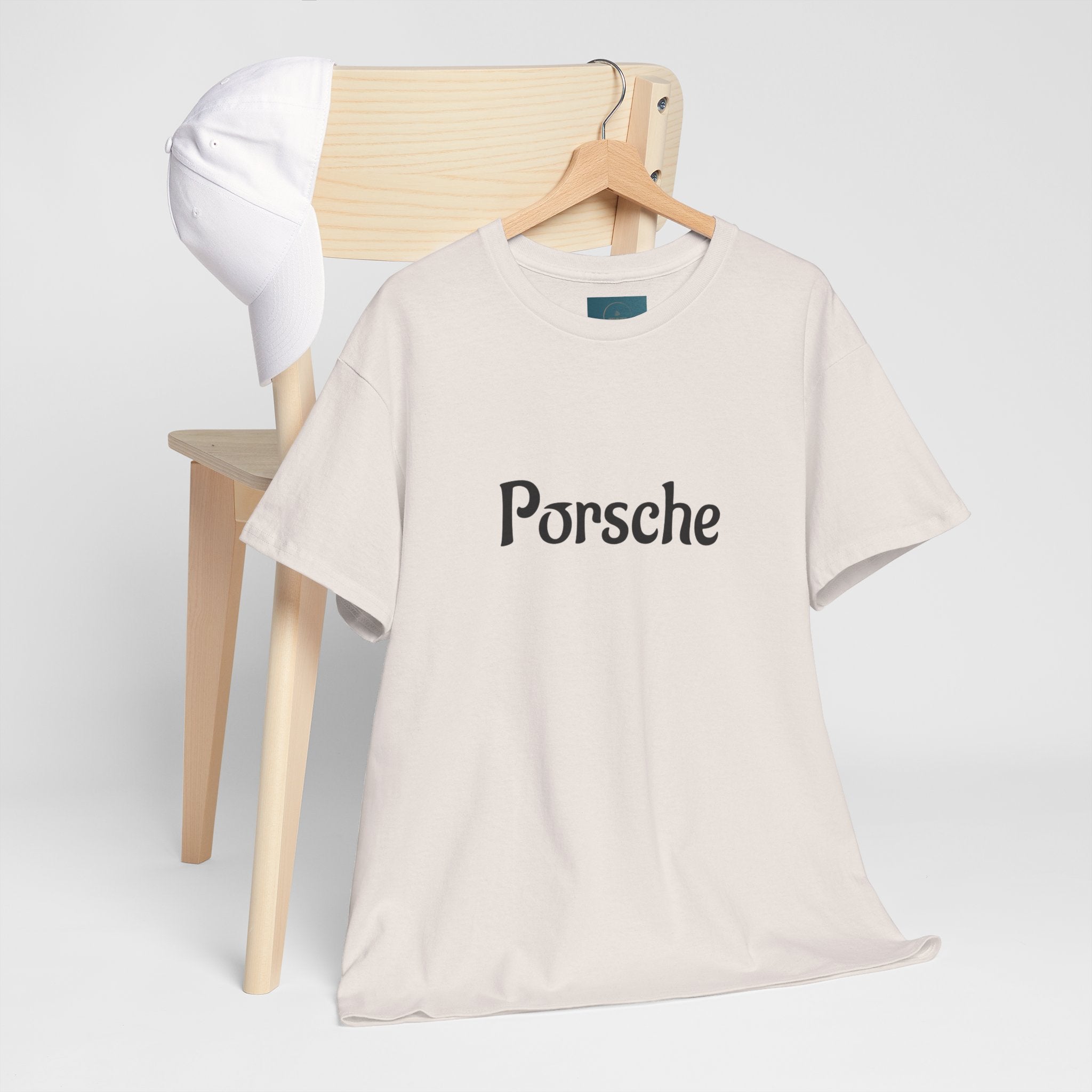 Beige t-shirt with 'Porsche' logo on a wooden chair against a white background