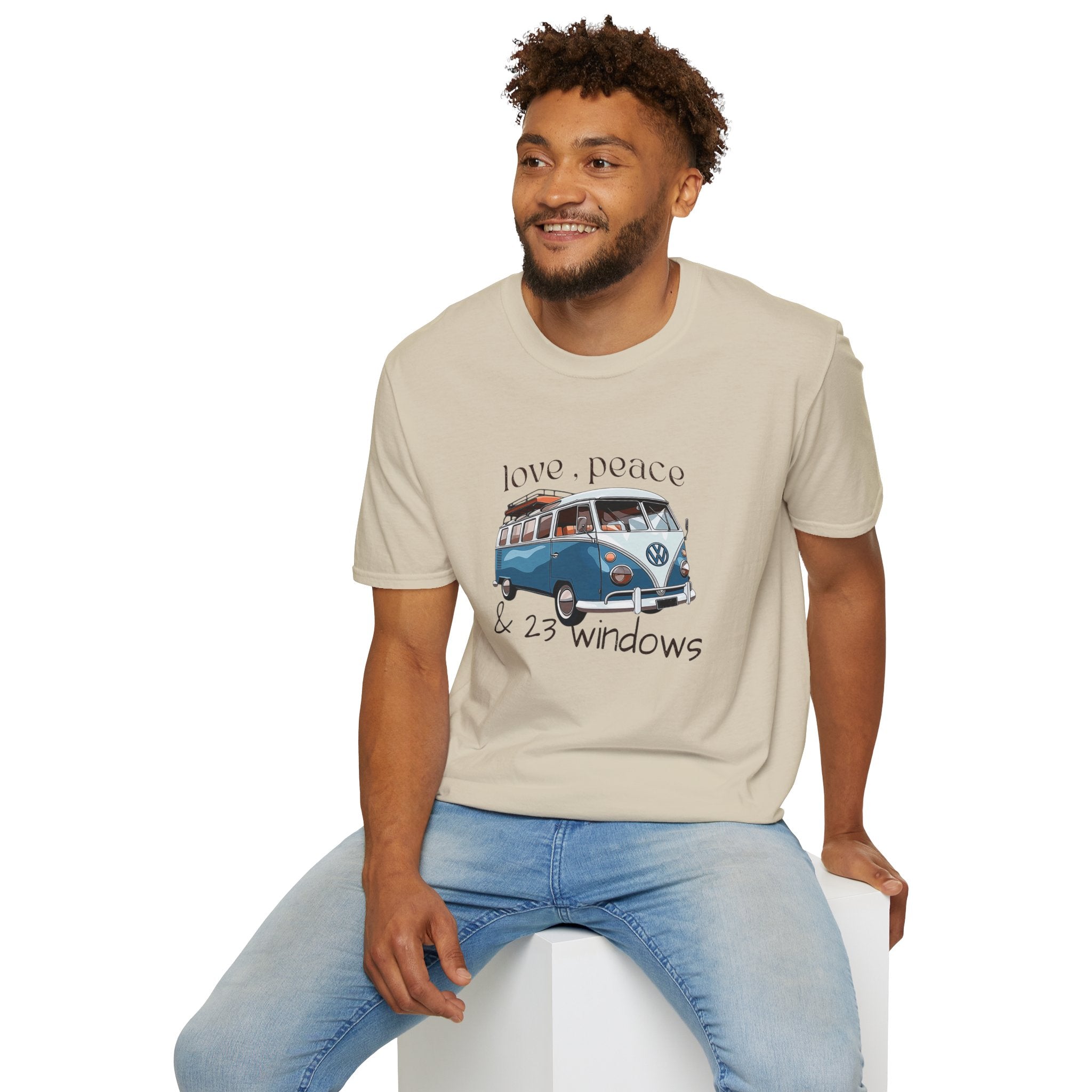 Man wearing a beige t-shirt with a vw bus graphic design sitting on a white stool against a white background