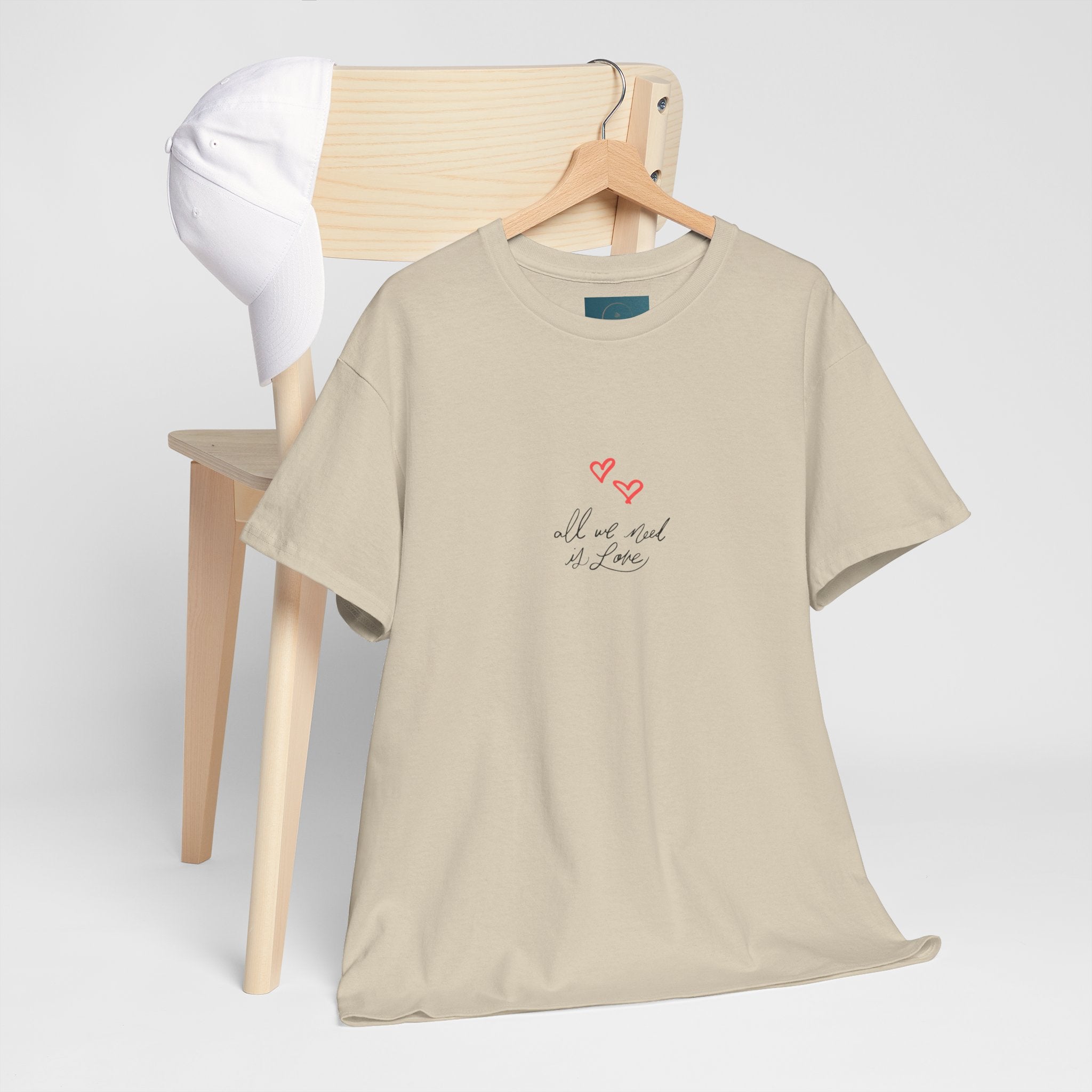 Beige t-shirt with text and heart design on a hanger against a white background