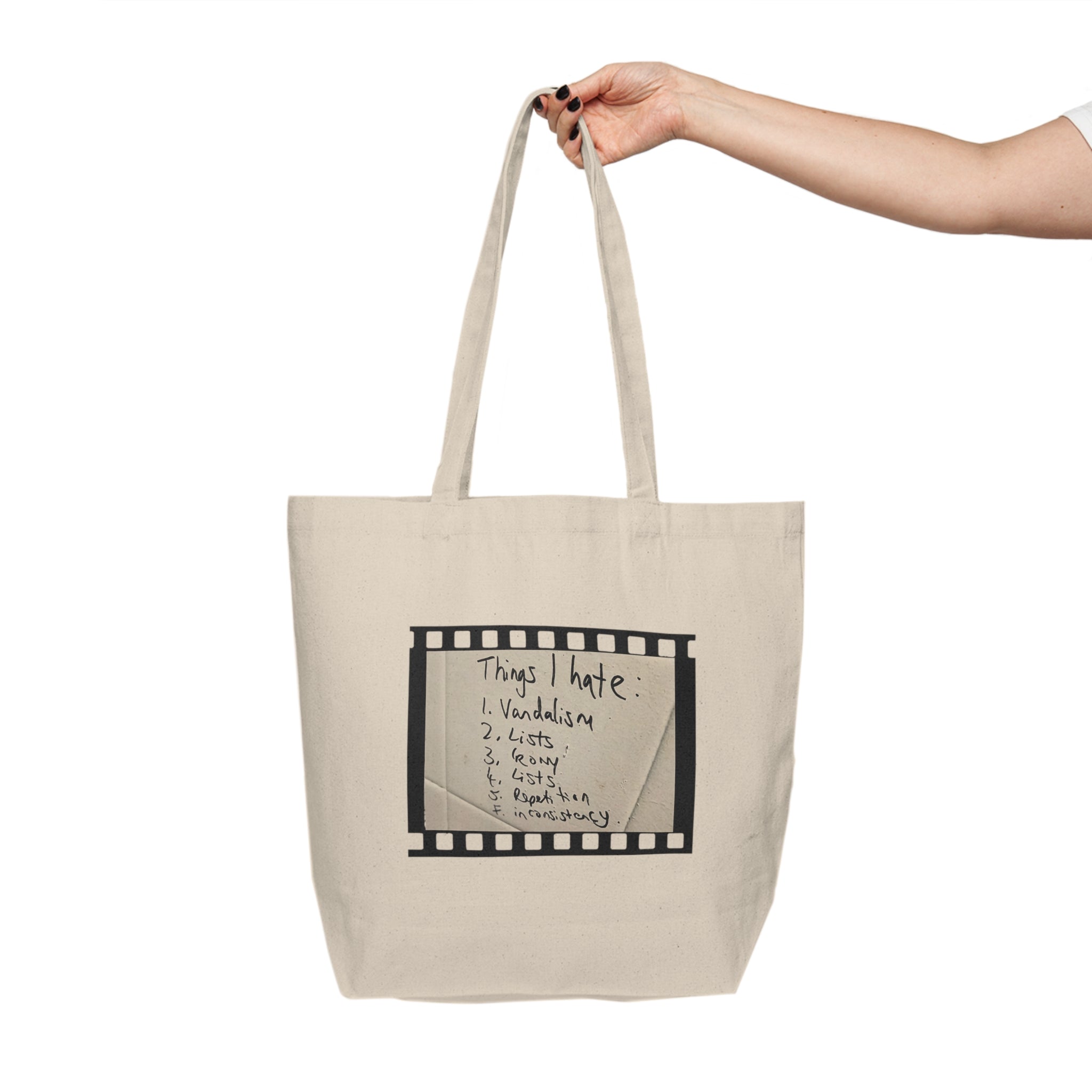 Beige tote bag with text held by a hand on a white background