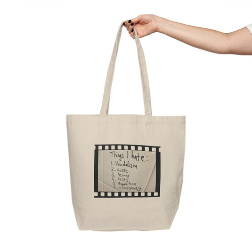 Beige tote bag with text held by a hand on a white background