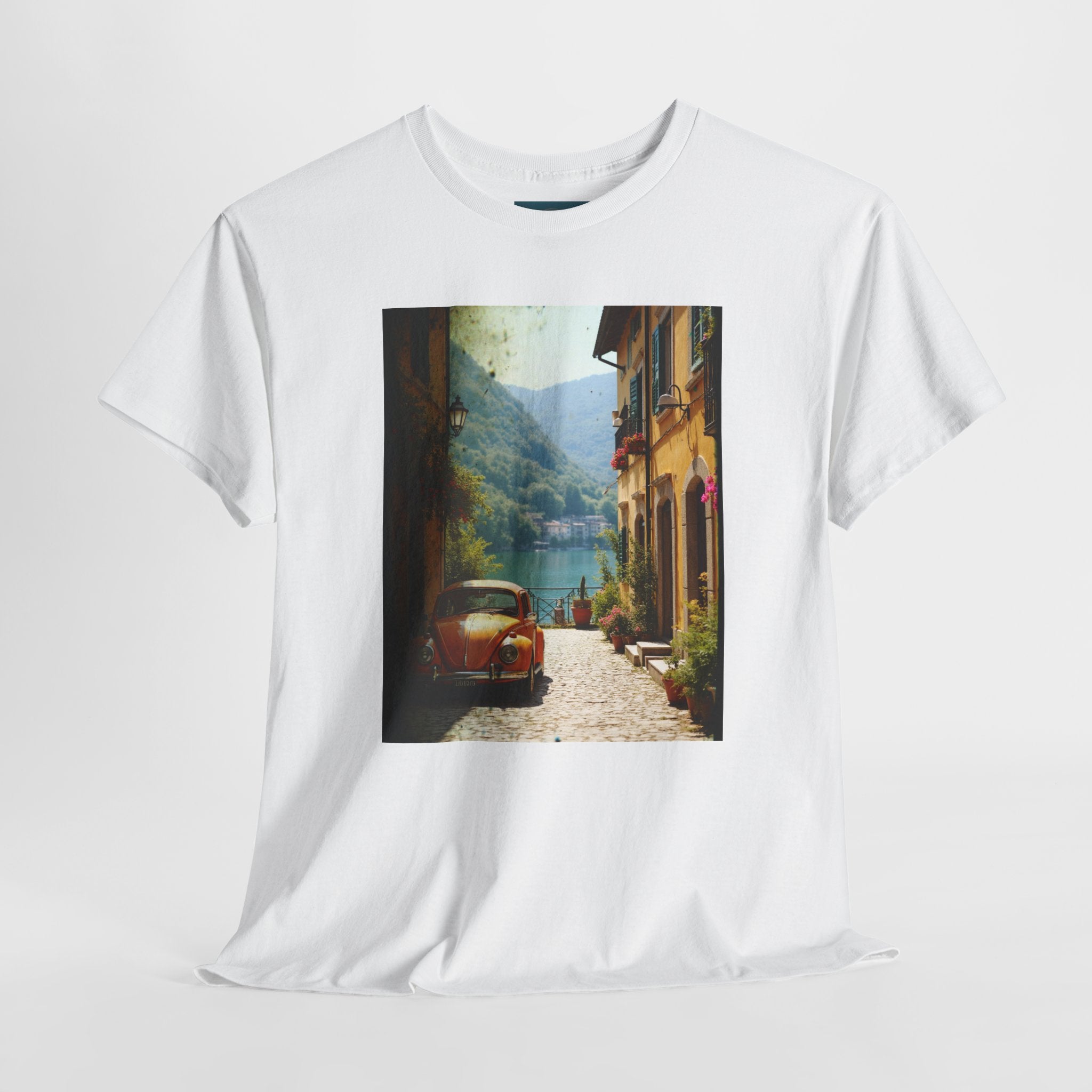 White t-shirt with a scenic print of a village street and VW Beetle car on a white background