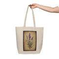 Beige tote bag with lavender design held by a hand on a white background