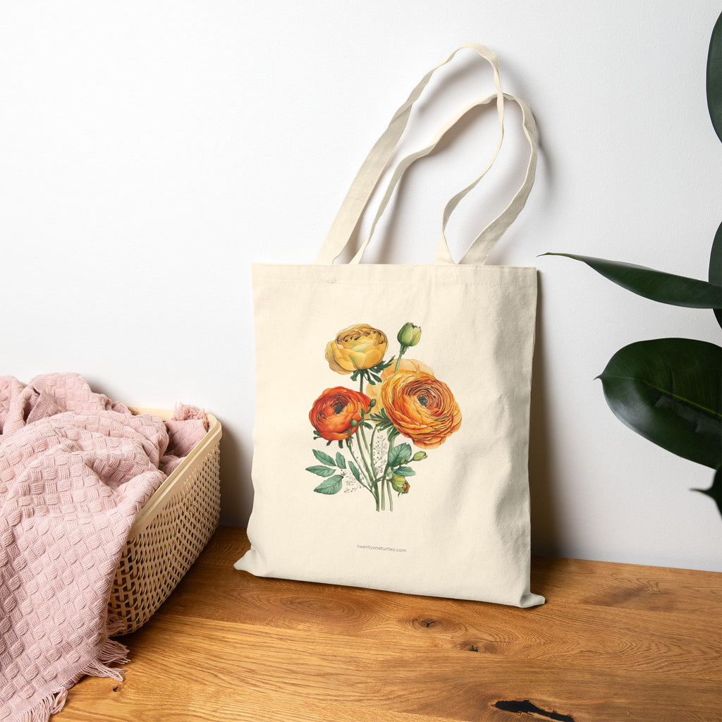 Tote bag with floral design on a wooden surface next to a basket and plant