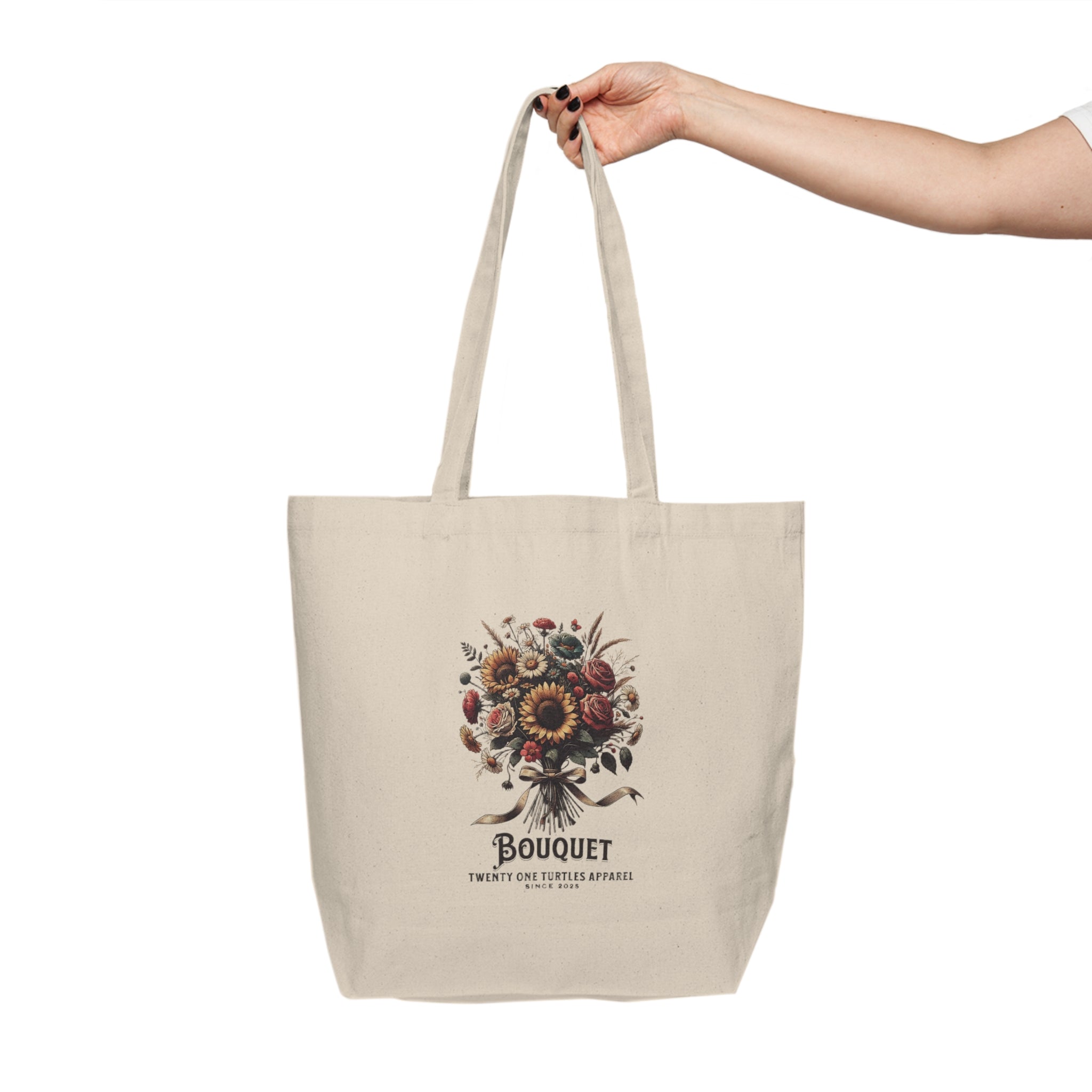 Beige tote bag with floral design and text held by a hand on a white background