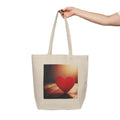 Tote bag with a red heart design held by a hand on a white background