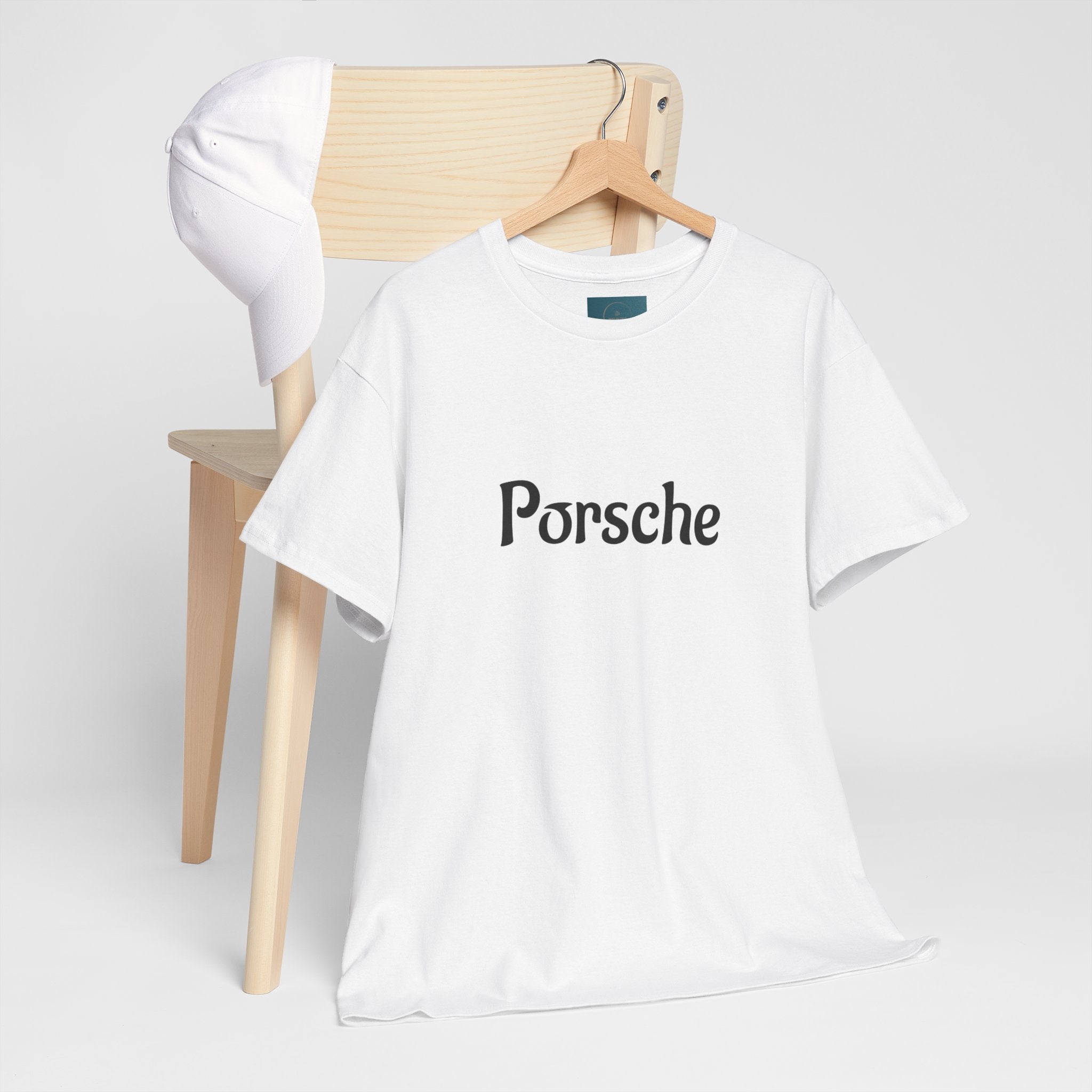 White t-shirt with 'Porsche' logo on a wooden chair against a white background