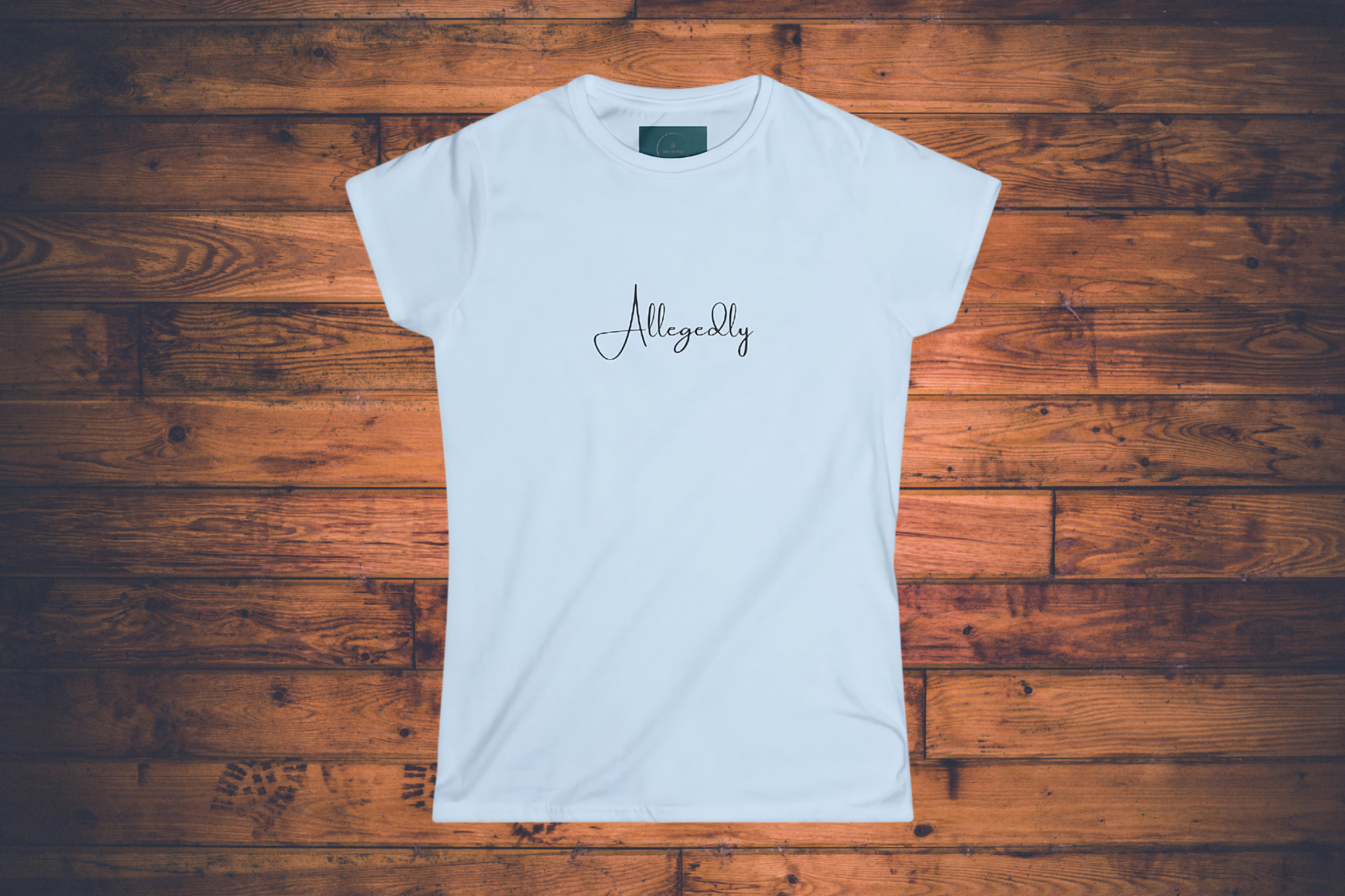 White t-shirt with 'Allegedly' printed on it on a wooden surface