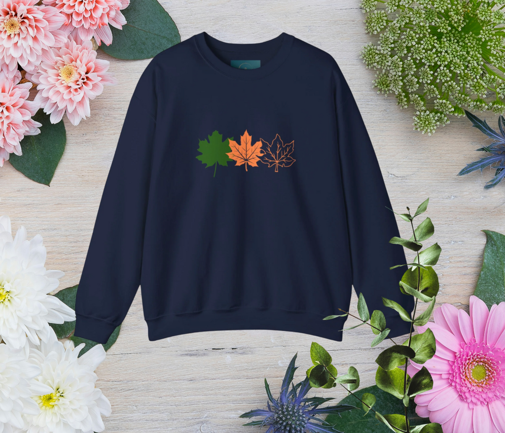 Navy blue sweatshirt with leaf design on a wooden surface surrounded by flowers