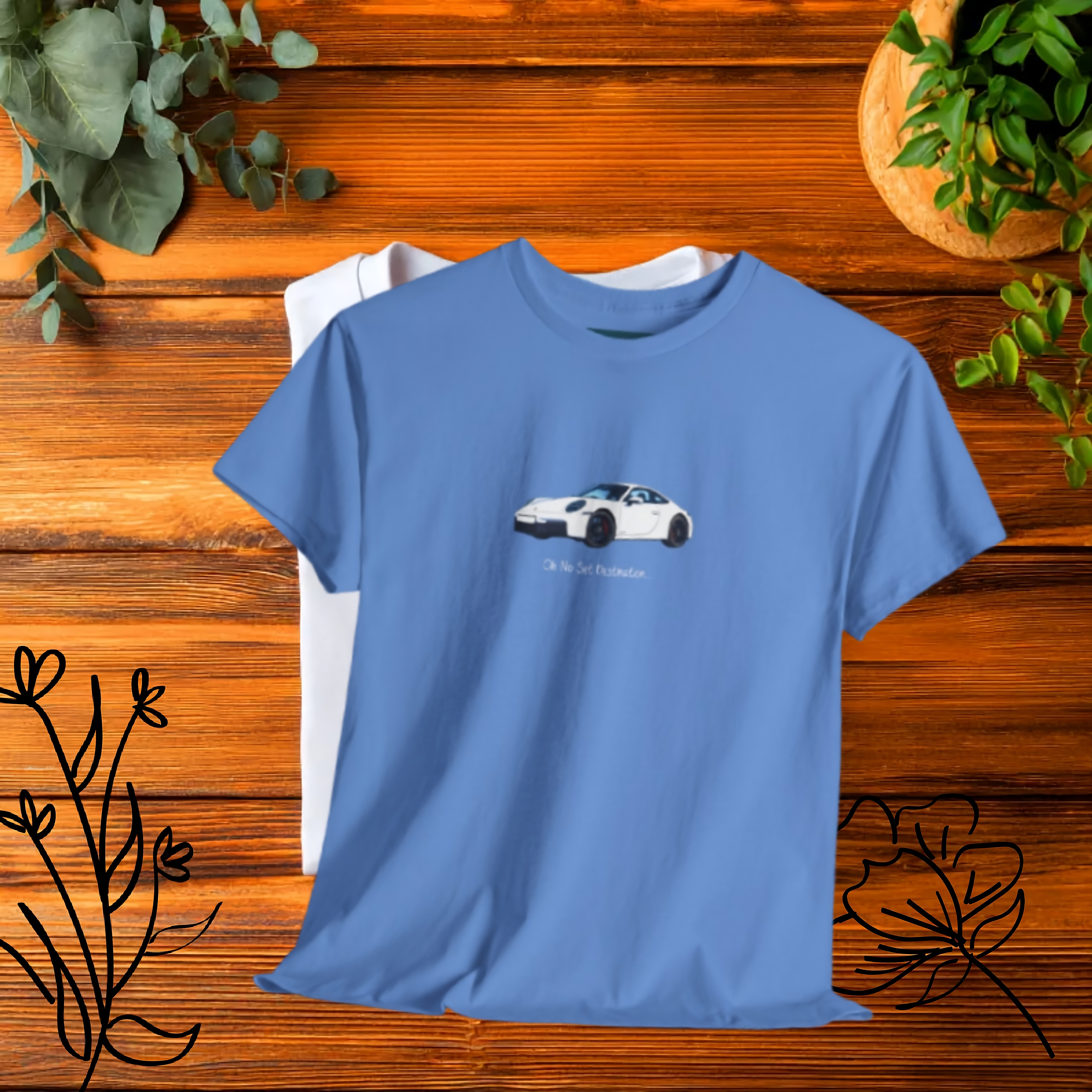 Blue t-shirt with a car graphic on a wooden surface with plants.