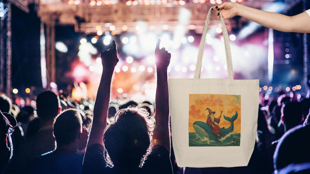 Person holding a PJ tote bag with a wizard on a whale design at a concert.
