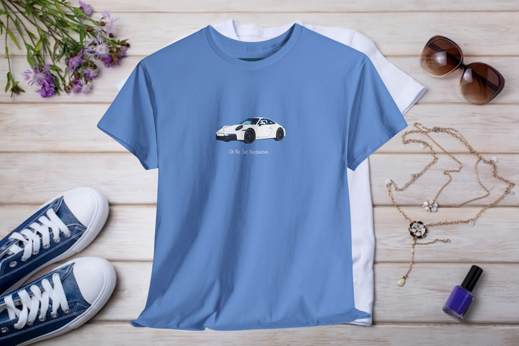 Blue t-shirt with a porsche car graphic on a wooden surface with shoes, sunglasses, and a necklace.