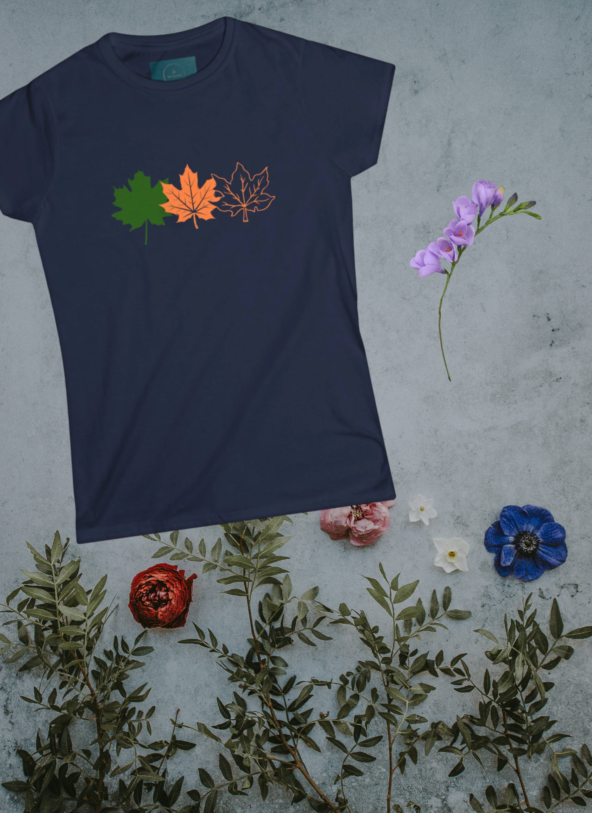 Navy blue t-shirt with leaf designs on a textured surface with flowers and leaves.